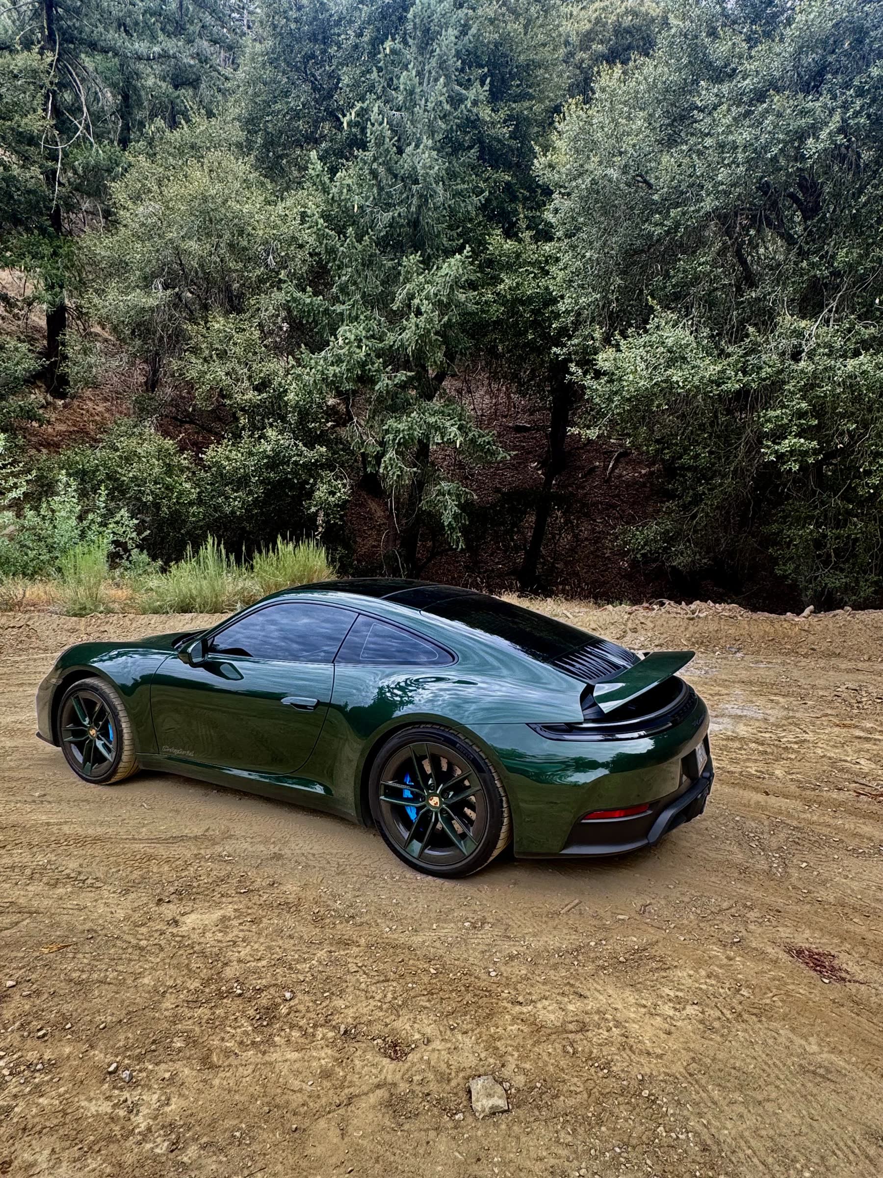 Rear three-quarter of the oak green 911 with the rear spoiler raised
